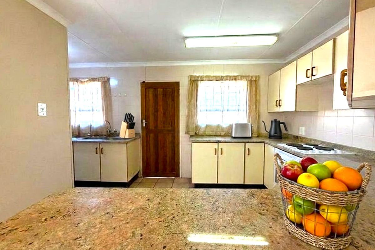 A functional kitchen featuring granite countertops, laminate cabinetry, and an electric hob, offering a practical layout with ample storage and preparation space.