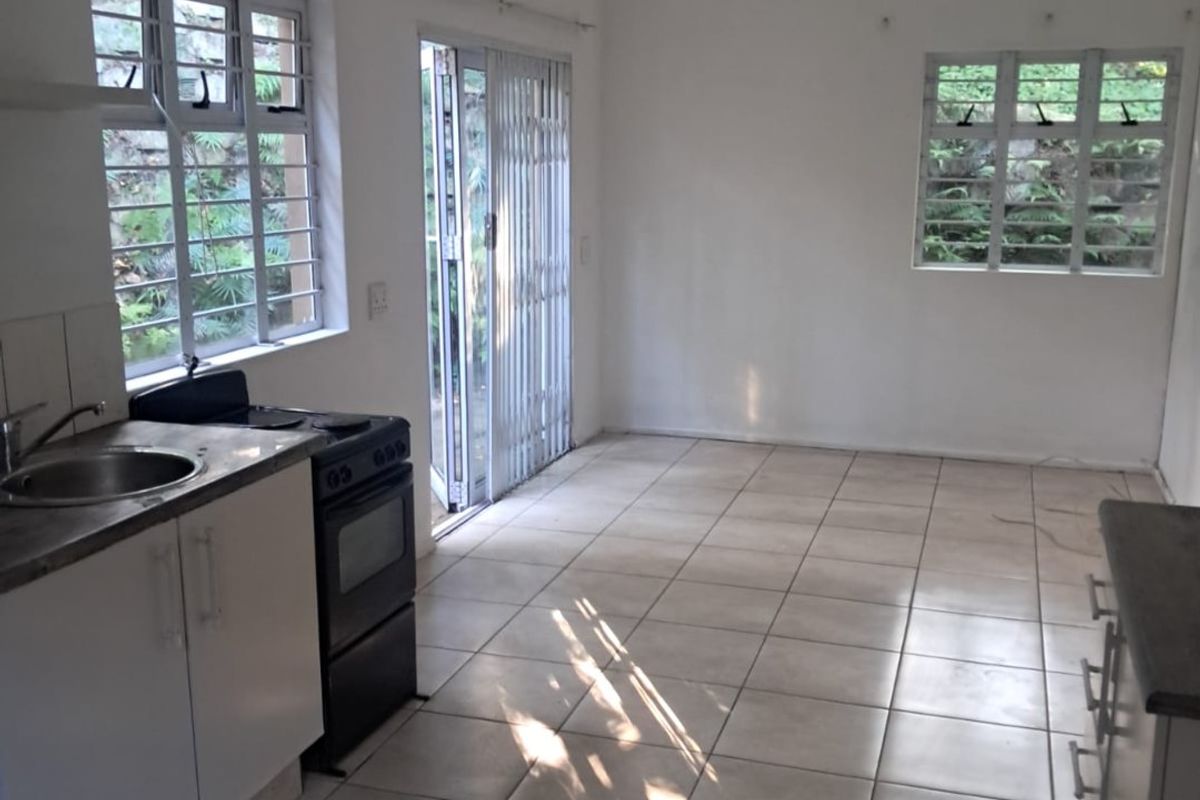 Open-plan kitchen and living area featuring tiled flooring, built-in cabinetry, and direct access to an outdoor space through a sliding glass door.