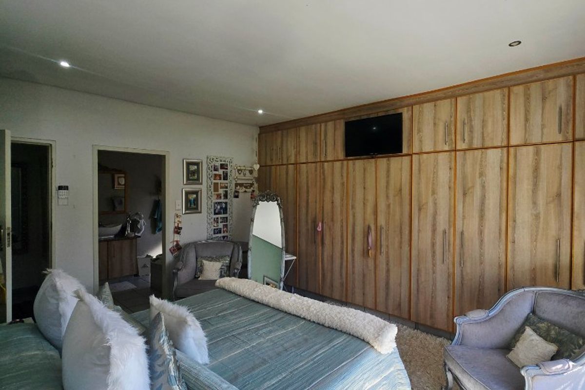 Spacious bedroom featuring extensive floor-to-ceiling built-in wooden cupboards, tiled flooring, and recessed downlighting.