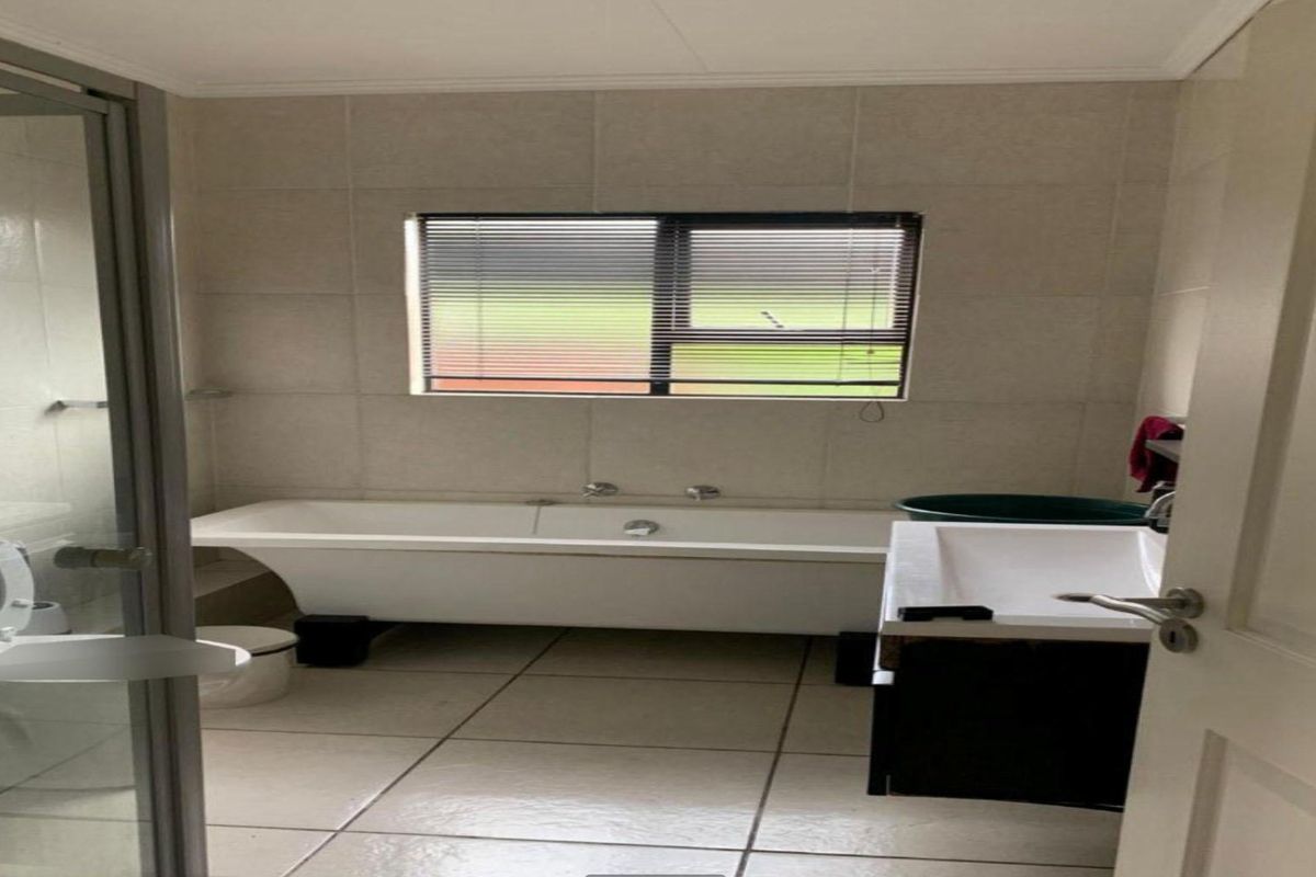 A functional bathroom featuring a freestanding bathtub, a separate shower enclosure, and tiled finishes throughout.