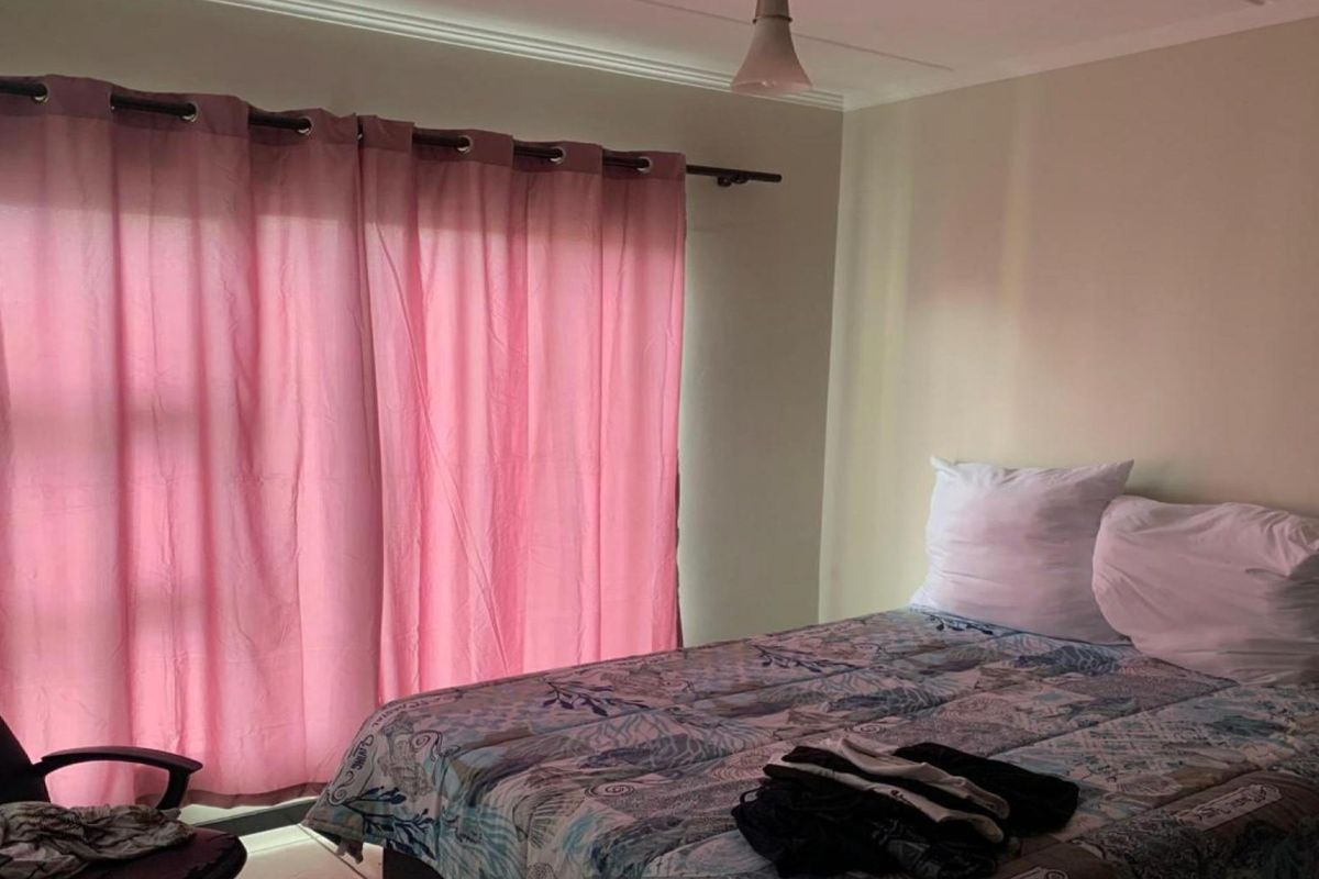 A functional bedroom featuring a window with curtain rod and ceiling lighting, providing a neutral space ready for personalization.