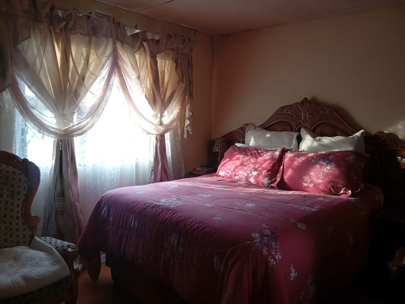 A bedroom featuring a window with curtains and basic wall and ceiling finishes.