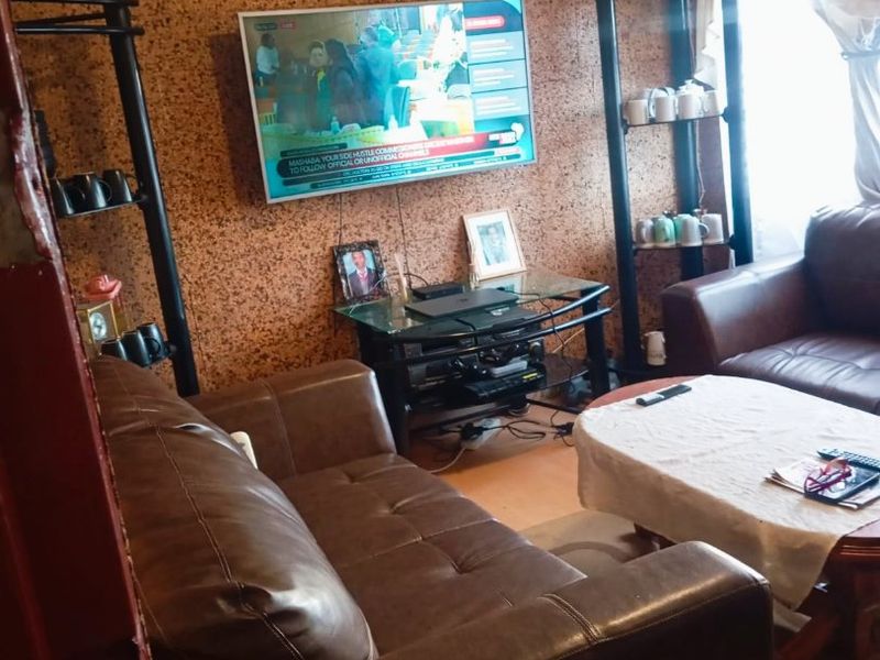 A living room featuring distinctive cork wall cladding and decorative ceiling cornicing, offering a dated aesthetic that could be modernized with updated finishes.