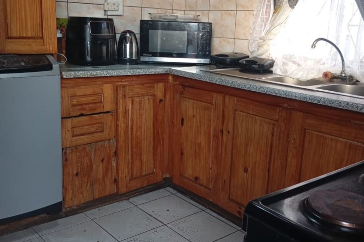 A functional kitchen featuring traditional wooden cabinetry, tiled backsplash, and a double sink with ample counter space.