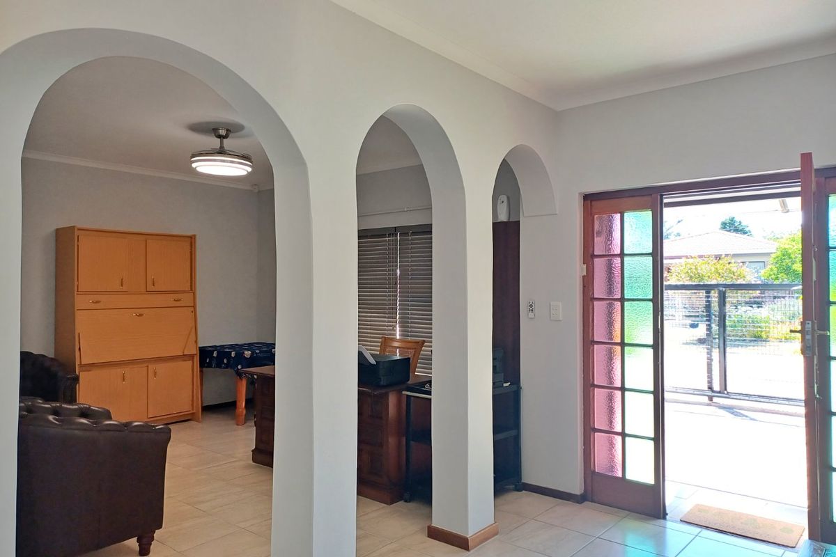 Living area featuring distinctive arched architectural dividers, tiled flooring, and a timber-framed glass door providing access to the exterior.
