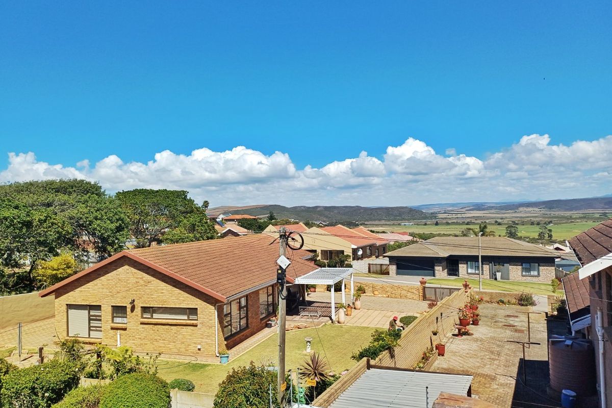 An elevated aerial view of a residential property featuring a brick house, paved patio area, and surrounding neighbourhood landscape.