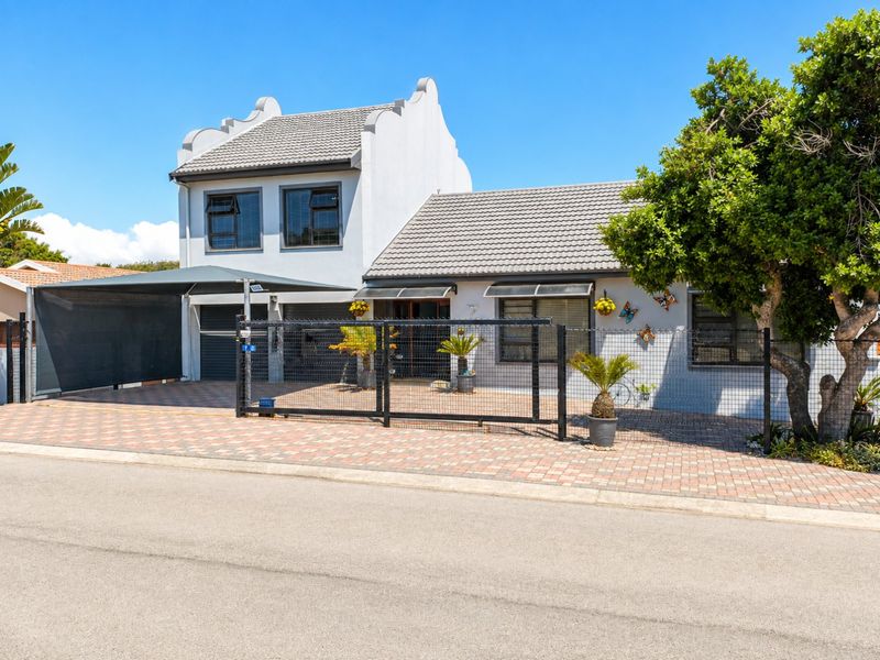 Front elevation of a two-story house featuring a paved driveway, secure metal fencing, and a shade sail carport.