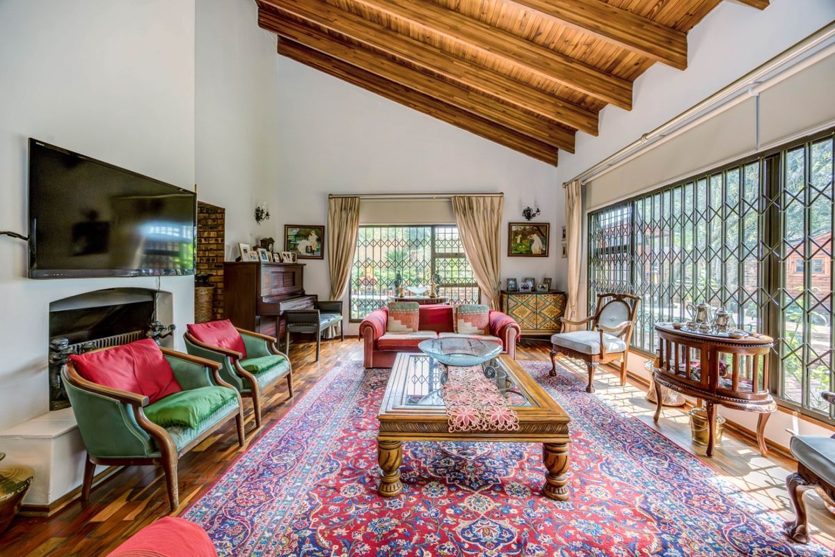 Spacious living room featuring a high vaulted timber ceiling with exposed beams, hardwood flooring, and a built-in fireplace, offering a warm and inviting atmosphere.