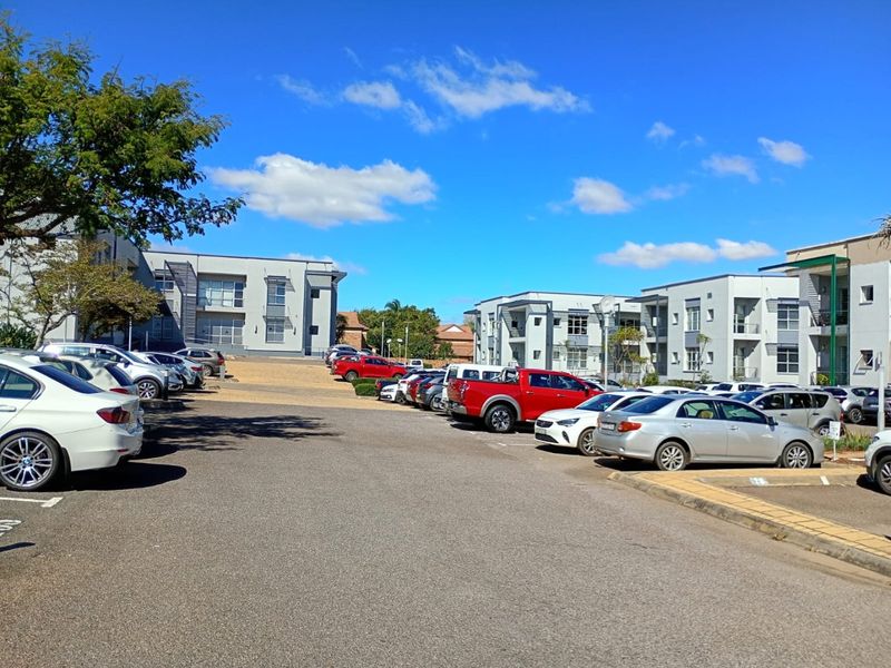 A view of the commercial property exterior featuring a paved parking area and multi-story office buildings under a clear sky.
