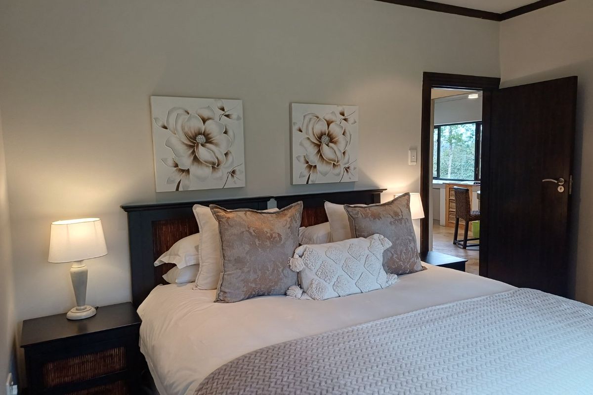 A well-maintained bedroom featuring dark wood door frames and trim, with a view into an adjacent room.