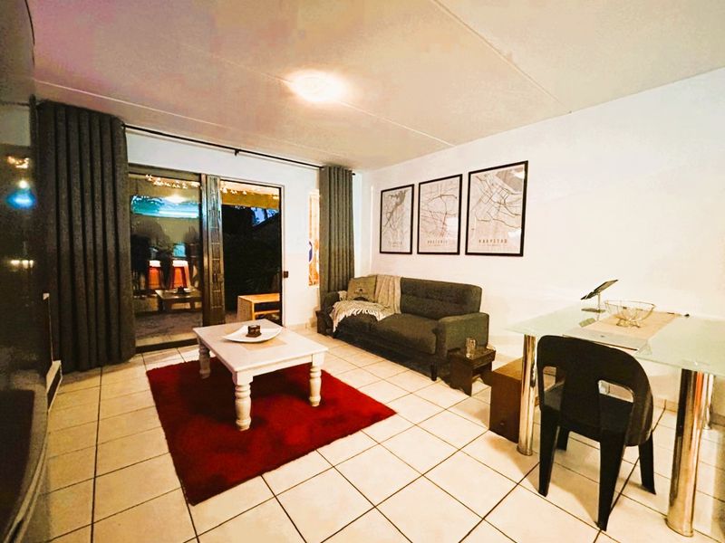 A living room featuring tiled flooring and a sliding glass door providing access to an outdoor area.