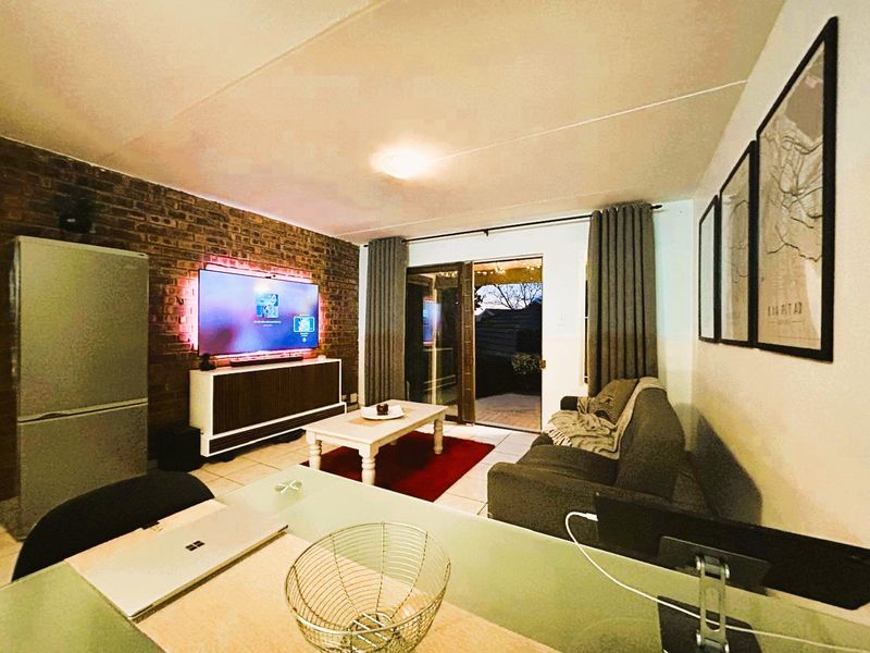 A cozy living room featuring an exposed brick wall, tiled flooring, and a sliding glass door providing access to an outdoor area.