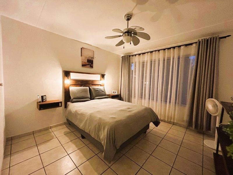 A well-lit bedroom featuring tiled flooring and a ceiling fan, offering a comfortable and functional living space.