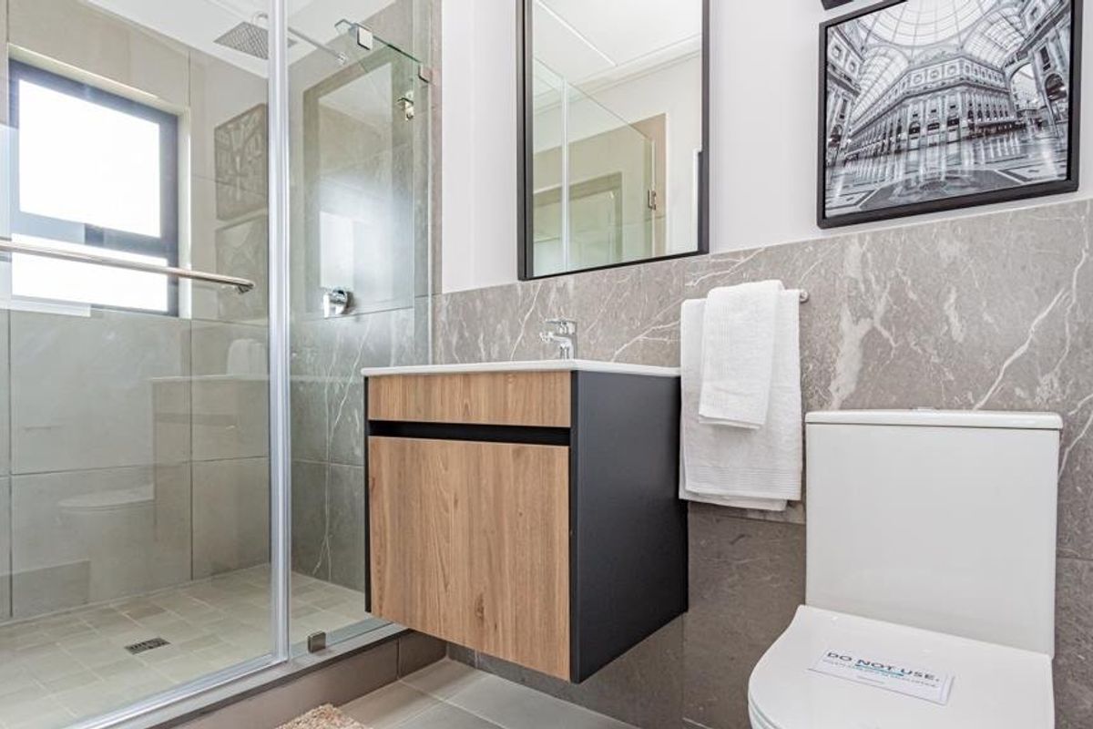 Modern bathroom featuring a walk-in glass shower, floating vanity with basin, and contemporary grey marble-look wall tiling.