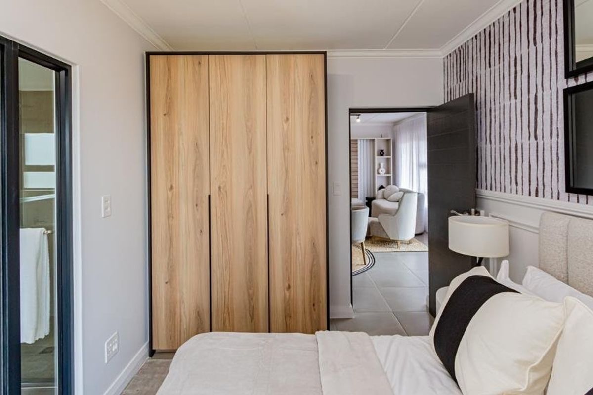 A well-maintained bedroom featuring a modern built-in wardrobe, tiled flooring, and direct access to an en-suite bathroom.