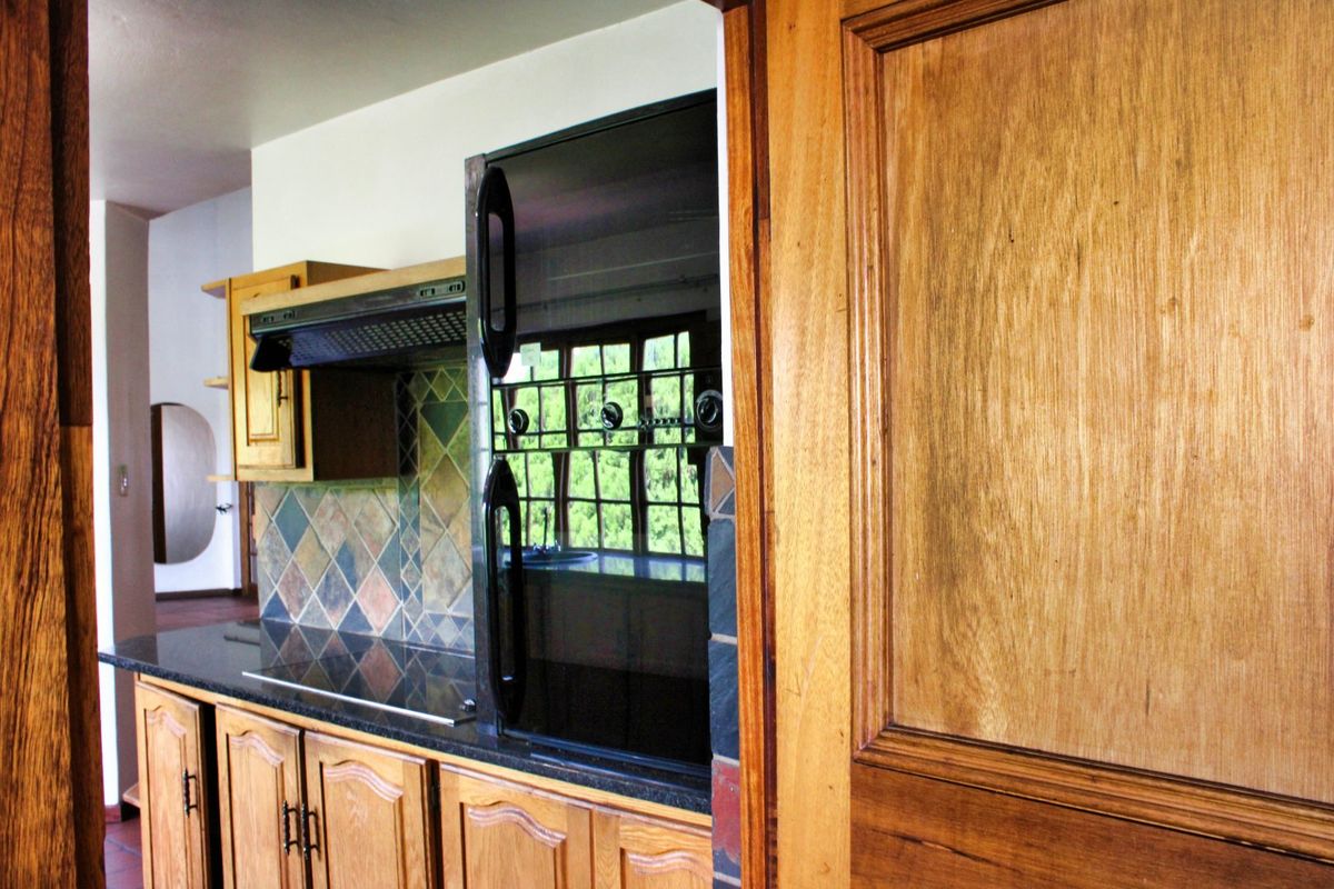A kitchen featuring traditional wooden cabinetry, stone countertops, a built-in oven, and a decorative tiled backsplash.