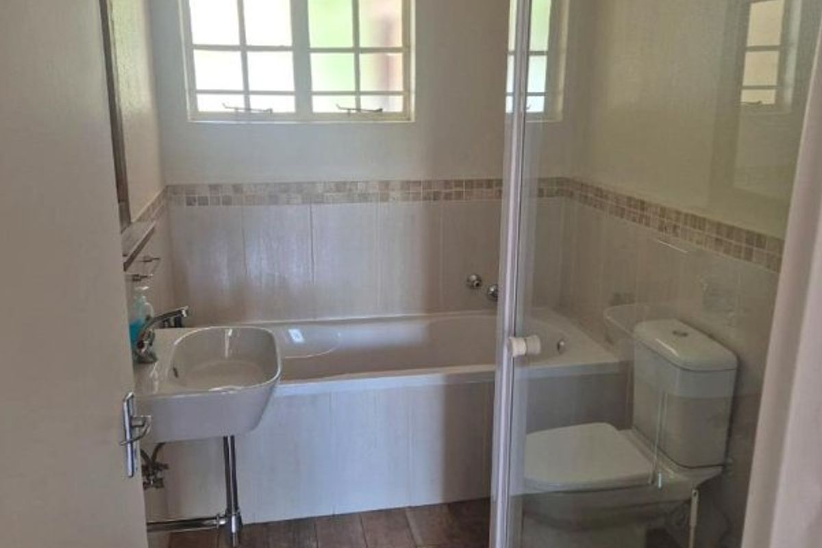 A clean, functional bathroom featuring a bathtub, separate shower enclosure, pedestal basin, and neutral tiled finishes throughout.