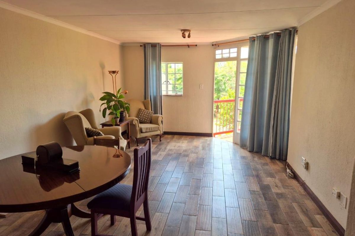 A living room featuring wood-look tile flooring, coved ceilings, and direct access to an outdoor balcony through a glass-paneled door.