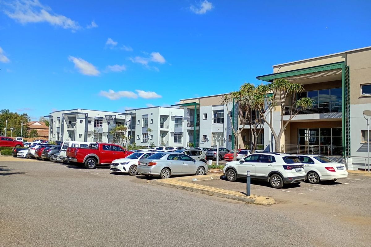 Exterior view of a modern multi-story residential complex featuring paved parking areas and building facades with balconies.