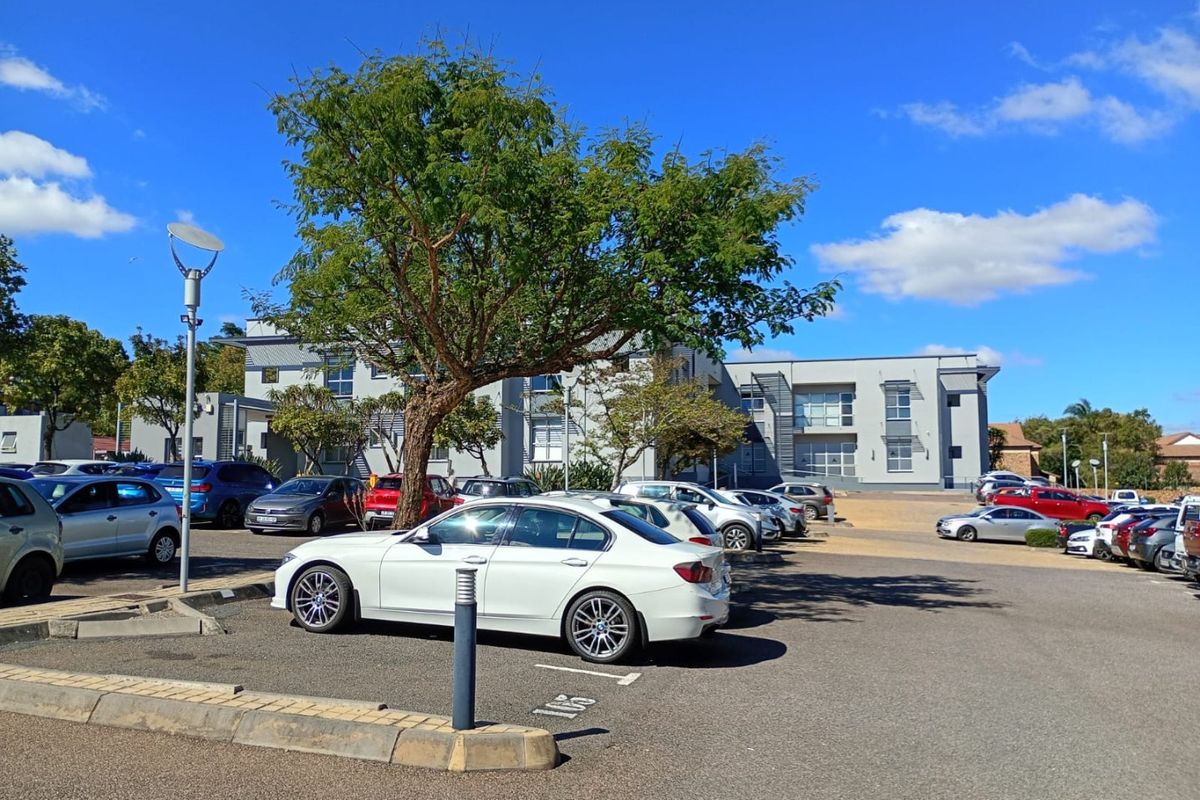 A view of the commercial property exterior featuring a paved parking area and the main building facade under a clear sky.