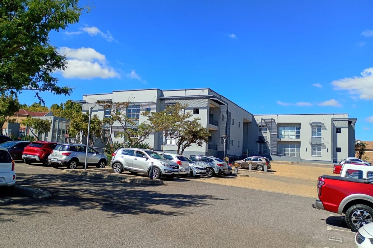 A view of the commercial building facade featuring a paved parking area and multi-story office structure with balconies.