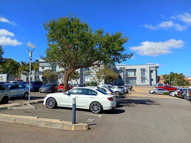 A view of the commercial property exterior featuring a paved parking area and the main building facade under a clear sky.