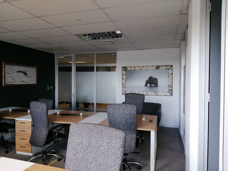 A professional office space featuring a suspended ceiling, recessed lighting, and a modern glass partition wall, providing a clean and functional work environment.