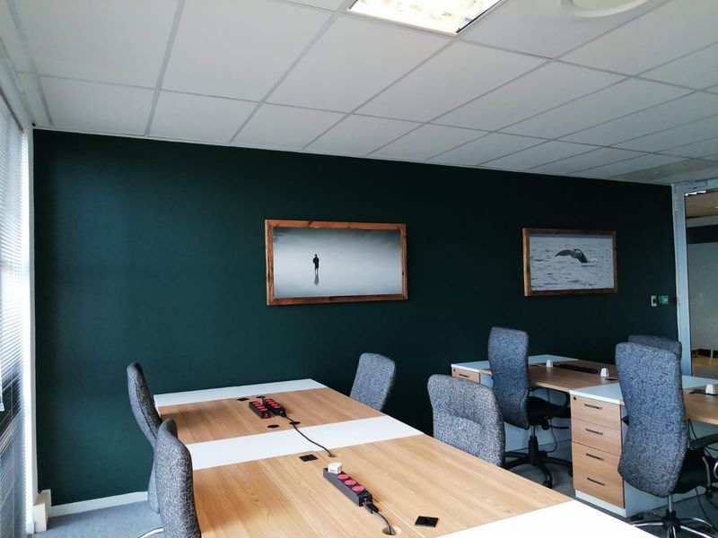 A modern commercial office space featuring a dark accent wall, suspended ceiling tiles, and integrated lighting, providing a professional work environment.