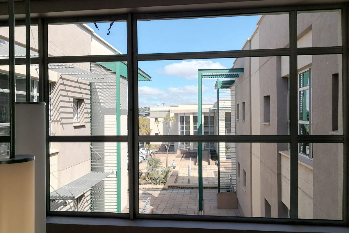 A view from an interior space looking out over a commercial courtyard with paved walkways and modern architectural building facades.