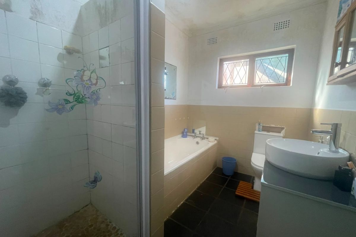 A dated bathroom featuring a separate shower, bathtub, toilet, and vanity basin, requiring cosmetic updates and ceiling repairs.