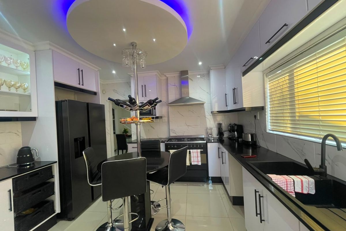 Modern kitchen featuring high-gloss cabinetry, marble-look backsplash, integrated appliances, and a unique circular ceiling feature with ambient LED lighting.