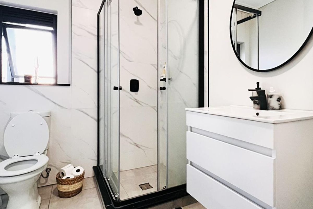 Modern bathroom featuring a glass shower enclosure, wall-mounted vanity with basin, and contemporary marble-look wall tiling.