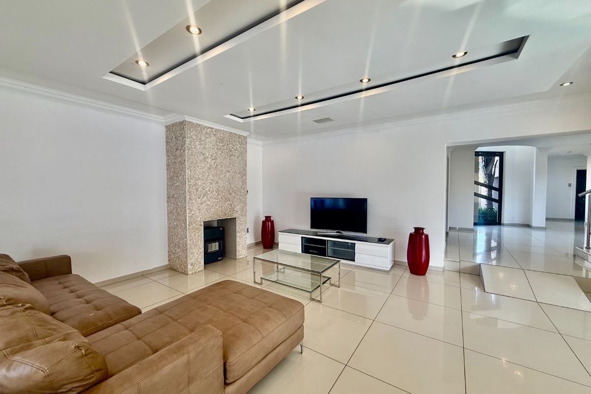 Spacious living room featuring polished tile flooring, a modern mosaic-tiled fireplace, and a recessed ceiling with integrated lighting.