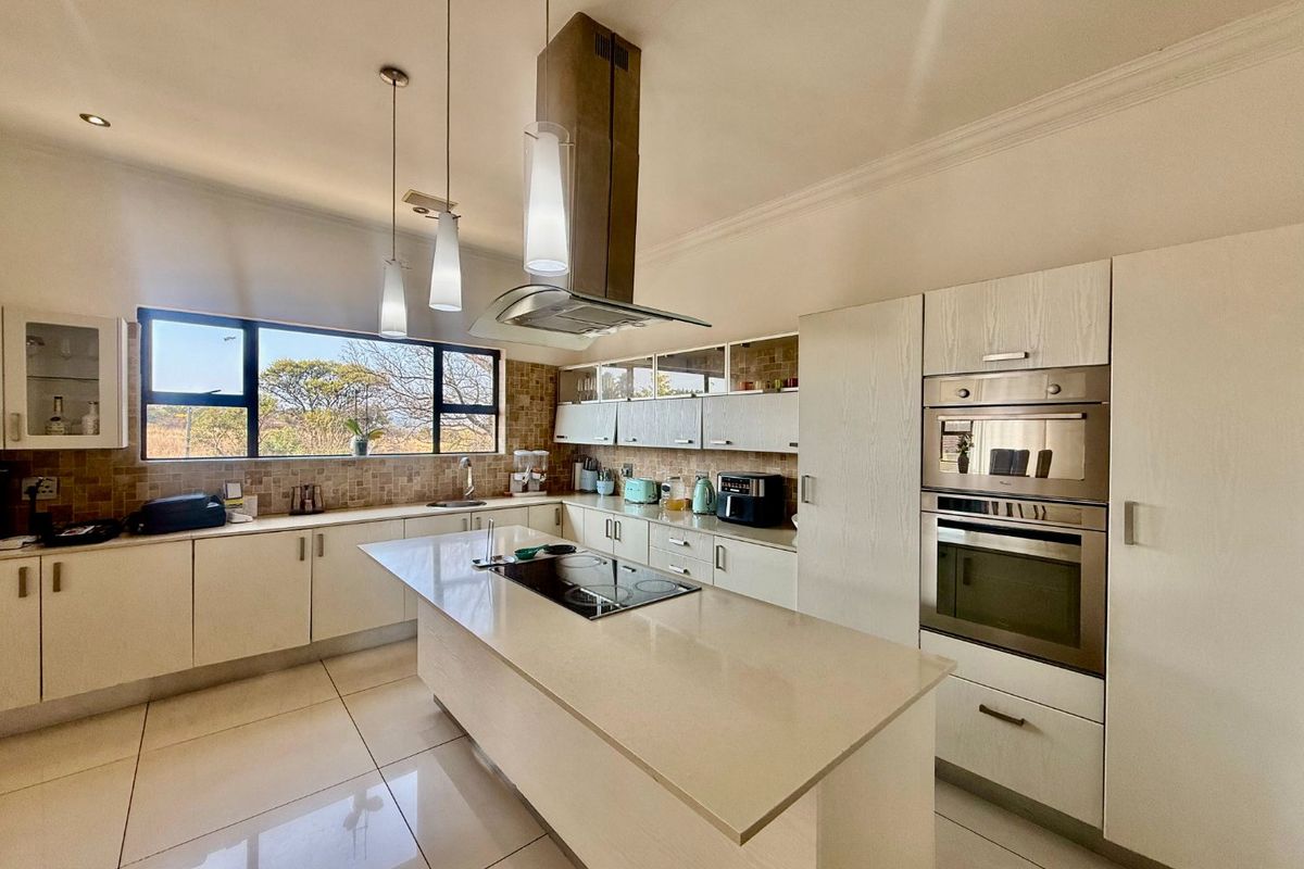 Modern kitchen featuring a central island, built-in oven and microwave, sleek cabinetry, tiled flooring, and large windows providing natural light and scenic views.