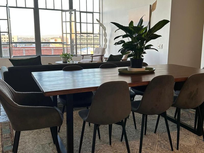 Spacious open-plan living and dining area featuring high ceilings, industrial-style windows, and exposed architectural elements, offering a bright and modern urban aesthetic.