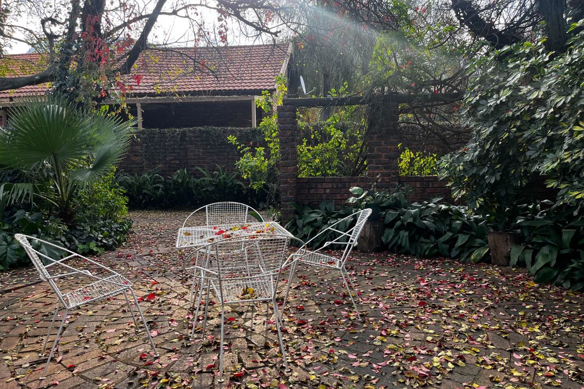 A charming outdoor patio area featuring traditional brick paving and established garden surroundings, providing a peaceful and private setting.