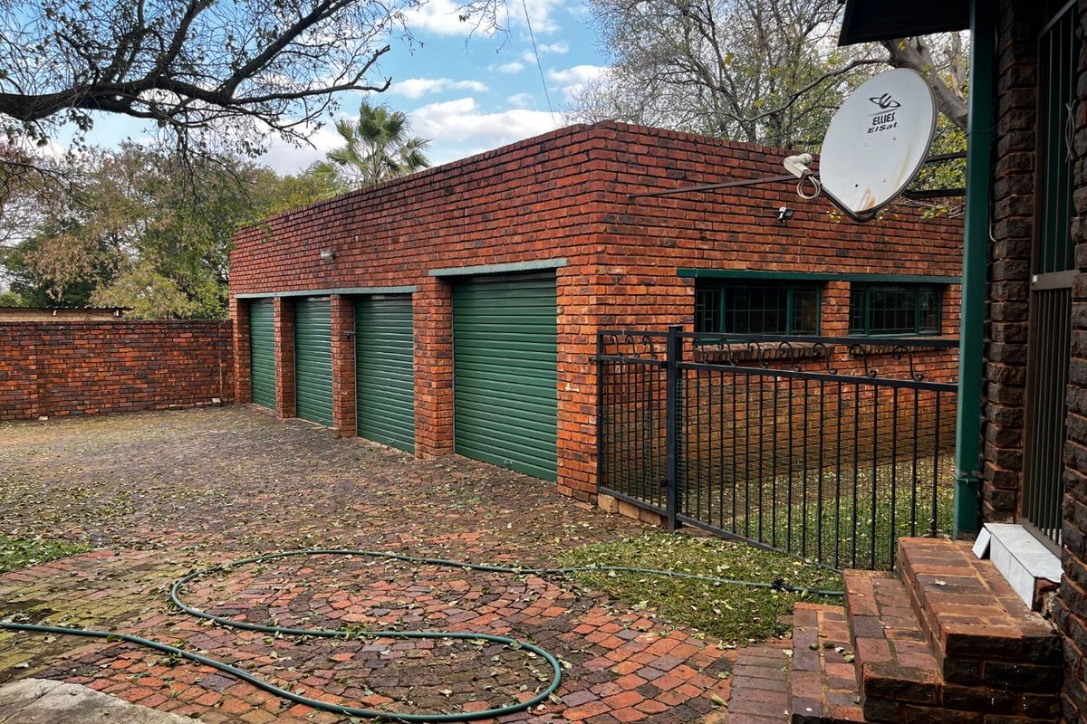 A detached triple garage featuring a face-brick exterior with green roller shutter doors and a paved driveway area.