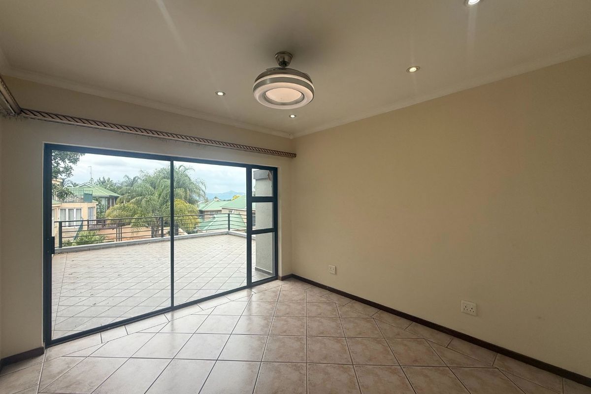 Spacious living area featuring tiled floors, recessed lighting, and large sliding glass doors opening onto a private balcony.