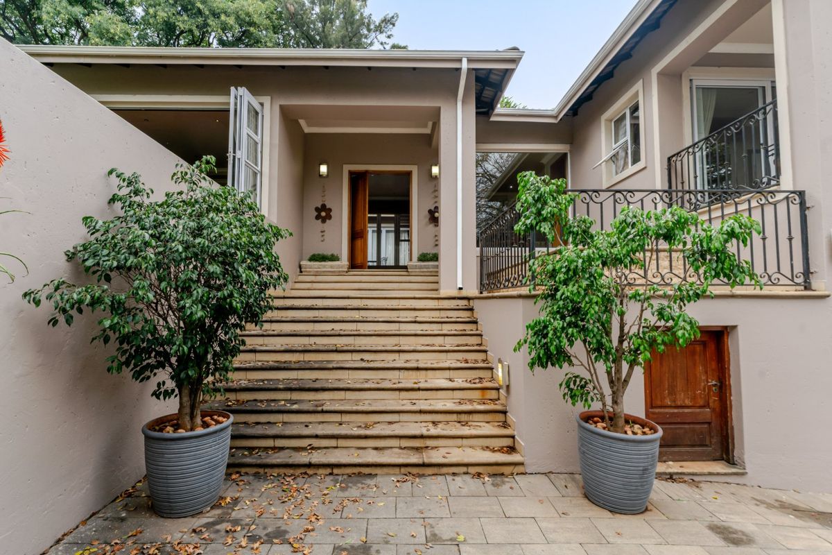 Rear exterior view featuring a wide stone staircase leading to the main entrance, complemented by a paved patio area and wrought iron railings.