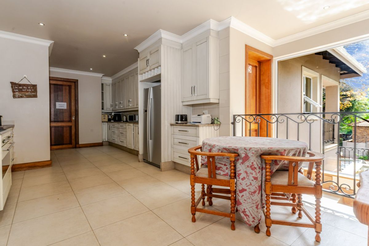 Spacious kitchen featuring light-toned cabinetry, tiled flooring, and direct access to an outdoor balcony area through a large opening.