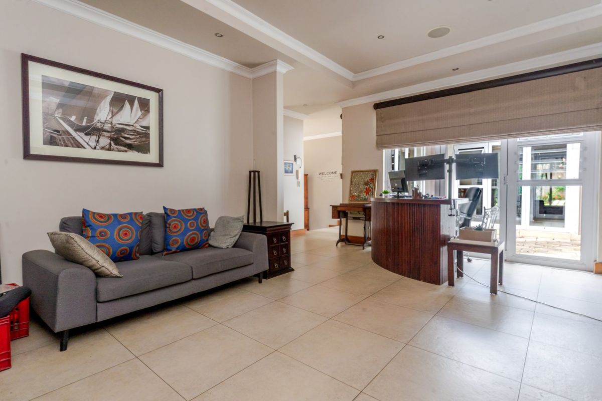 A spacious living area featuring neutral tiled flooring, recessed ceiling lighting, decorative coving, and large sliding glass doors providing access to the exterior.