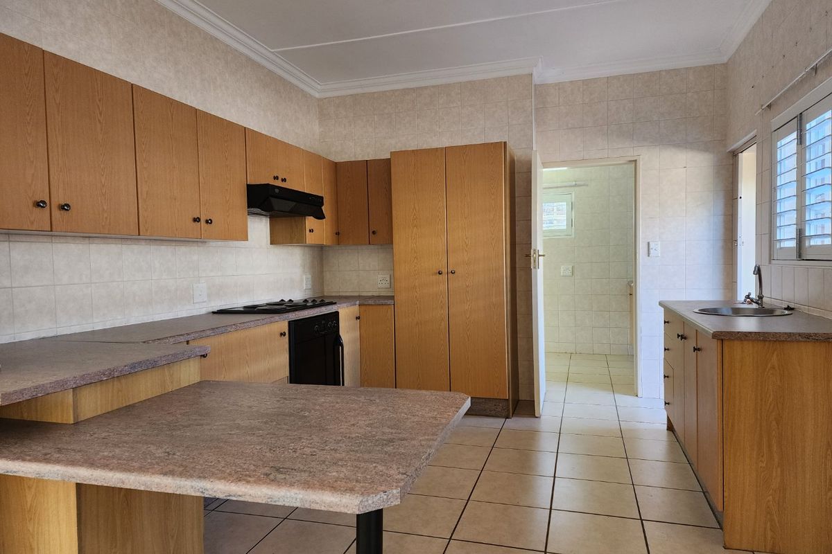A functional kitchen featuring laminate cabinetry, built-in oven, hob, extractor fan, and tiled flooring, offering a clean, neutral space ready for modern updates.