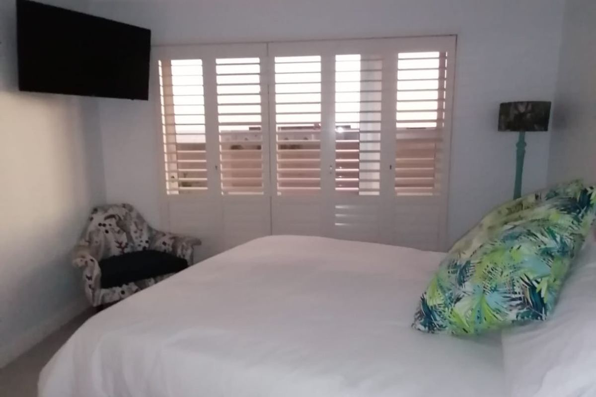 A bedroom featuring white plantation shutters, coving, and a flush mount ceiling light.