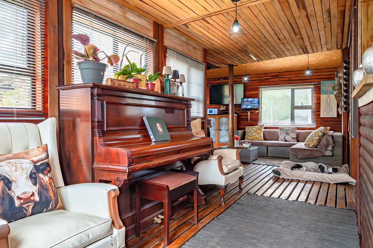 A rustic living room featuring warm timber wall cladding, a timber ceiling, and unique timber slat flooring, creating a cozy and character-filled atmosphere.