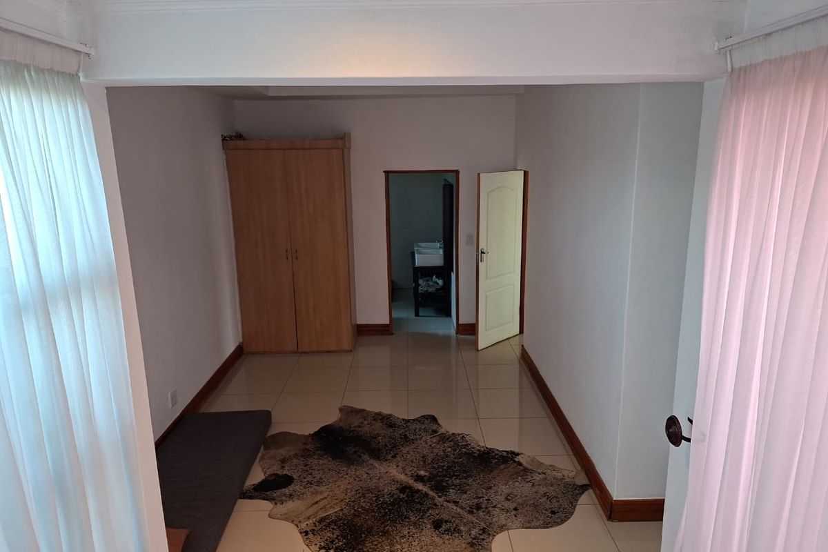 A bedroom featuring tiled flooring, built-in wardrobe, and direct access to an en-suite bathroom.