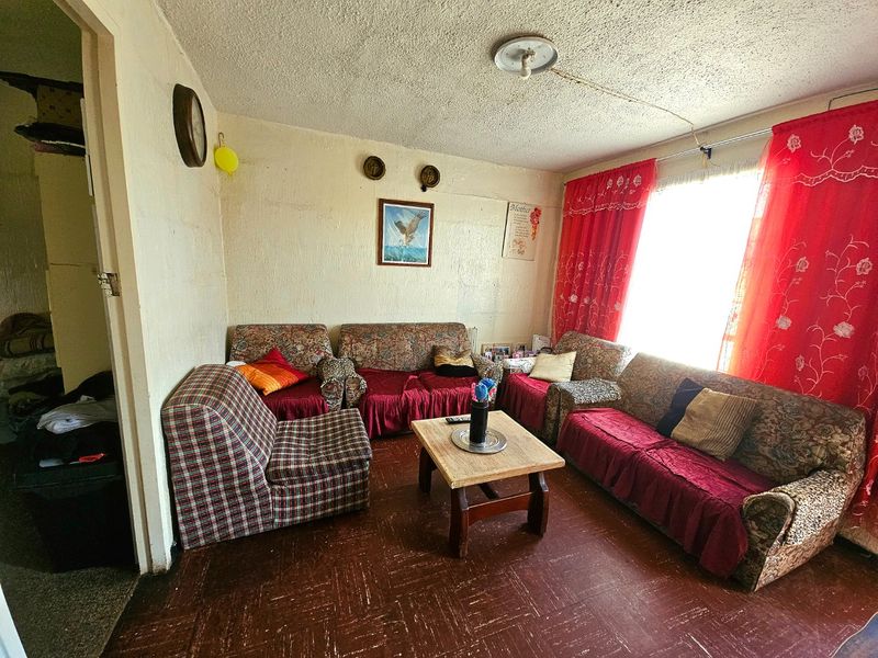 A living room featuring textured ceilings and vinyl floor tiles, offering a dated interior space with potential for modernization and cosmetic updates.