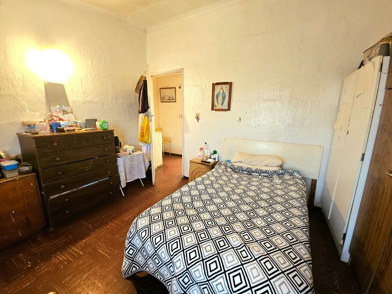 A bedroom featuring built-in wardrobe storage and traditional cove cornicing, requiring cosmetic updates to the wall finishes and flooring.