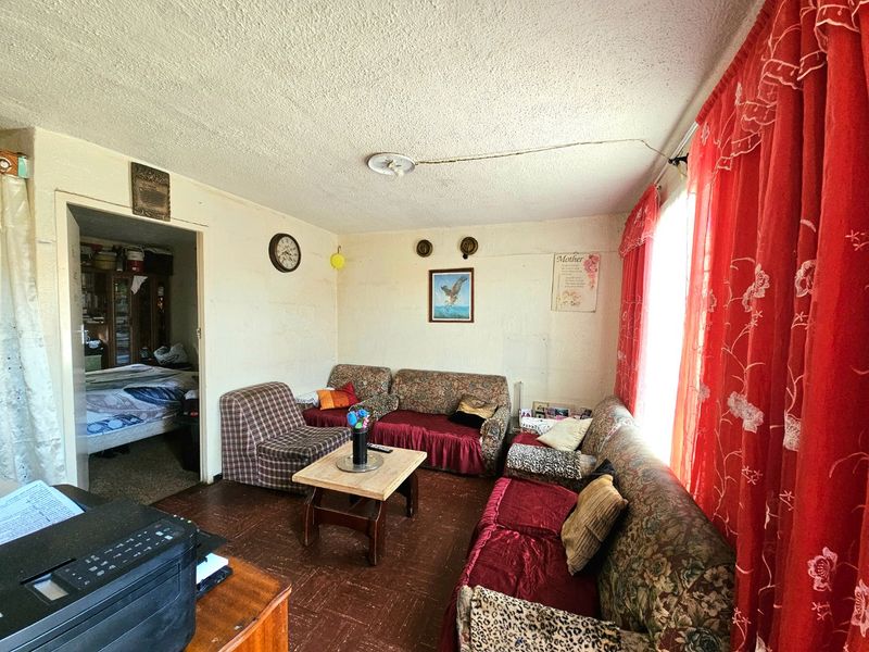 A living room featuring textured ceilings and vinyl floor tiles, offering a dated interior space with potential for modernization and renovation.
