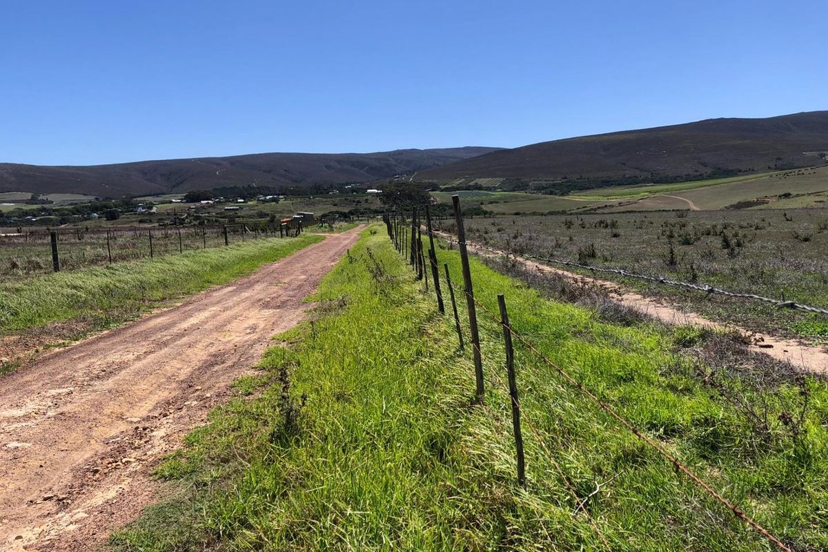A scenic view of the farm landscape featuring a dirt access road and traditional barbed wire fencing stretching across the open fields.