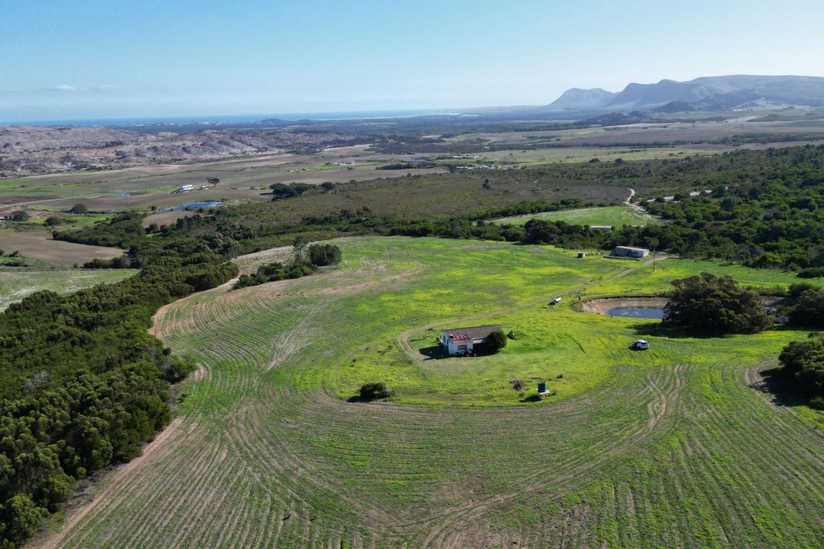 Aerial view of a rural farm property featuring expansive open fields, a small dam, and the main dwelling set within the landscape.